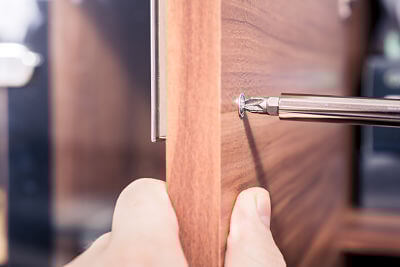 Screwdriver driving screw into cabinet at close range