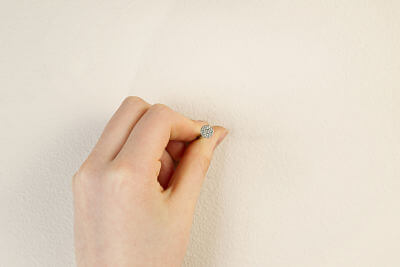 Hand holding nail to beige wall